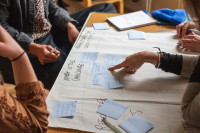 the image shows three people working at a table. only their hands are visible, as they point at a piece of paper on climate strategies