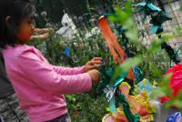 A girl in a garden with coloured paper artwork