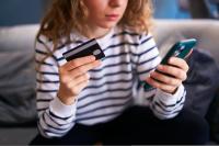 Worried woman with smartphone and debit card