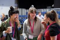 Artists and delegates networking. Image depicts three people stood together at a work event laughing.