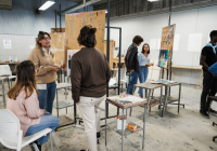 Mature teacher working with art students during painting class at school