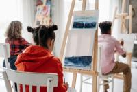 Young people painting on easels