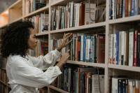 A woman looks through books on a library shelf