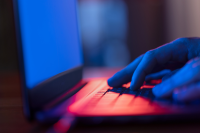 A hand on a glowing laptop