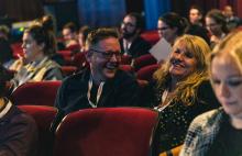 A photo of a man and a woman laughing in an auditorium