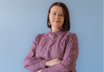 Lori Anderson stands in front of a blue background