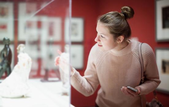 Woman visitor using phone in museum