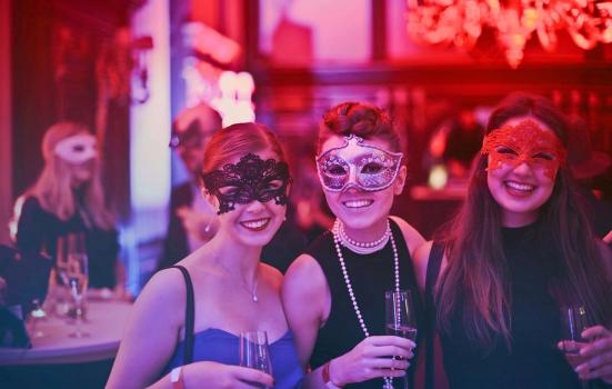 Three masked women at a drinks party