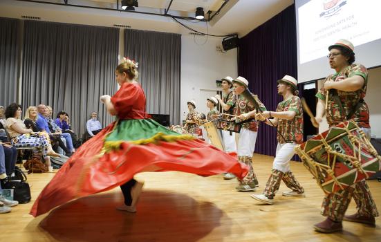 Drummers on stage following behind a woman in a huge twirling skirt