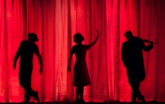 Silhouettes of three people on a stage curtain