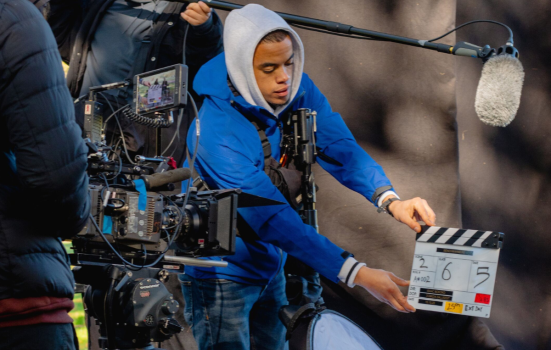 A young person operates a clapper board for filming