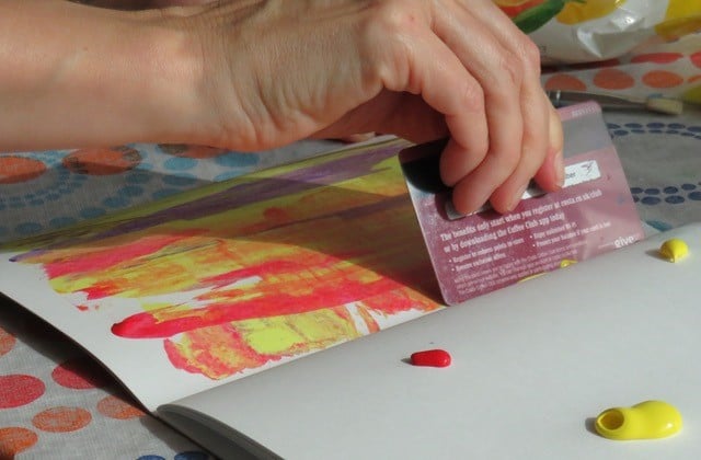 Photo of person scraping paint in exercise book with bank card