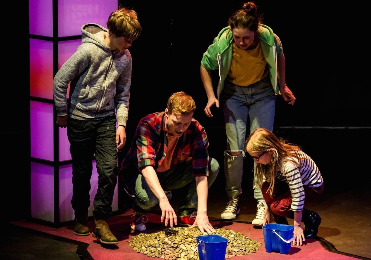 Actors collecting coins off the floor during a production