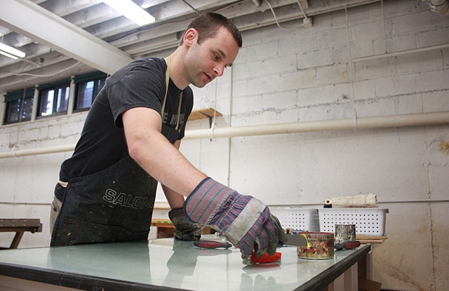 A man wearing gloves working with tools at a table