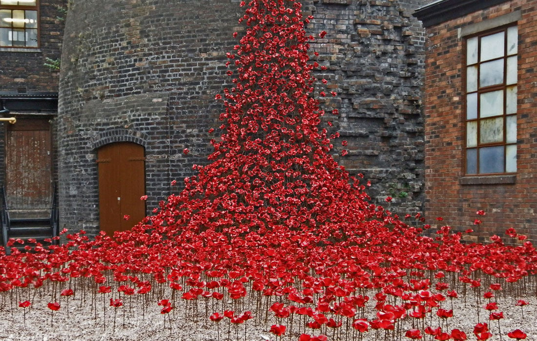 Photo of cermaic poppies cascading out the window of a stone building