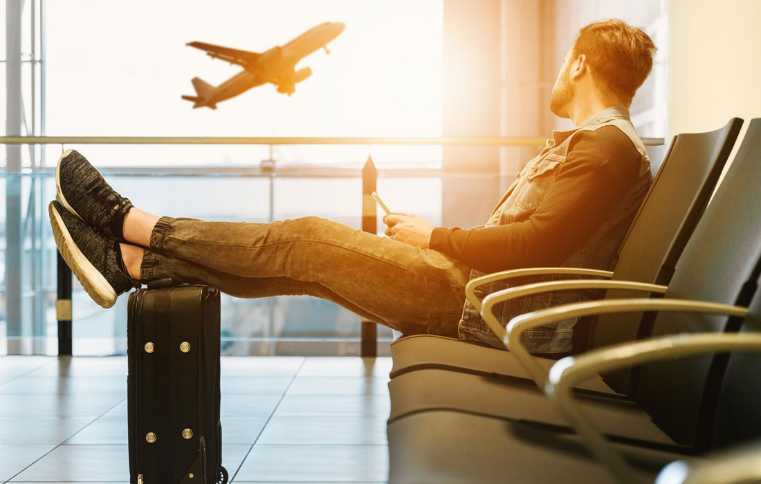 Photo of a man sitting in an airports, watching a plane take off