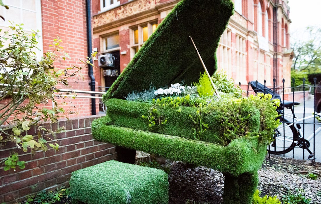 Photo of a grand piano as a garden feature, covered in plants.