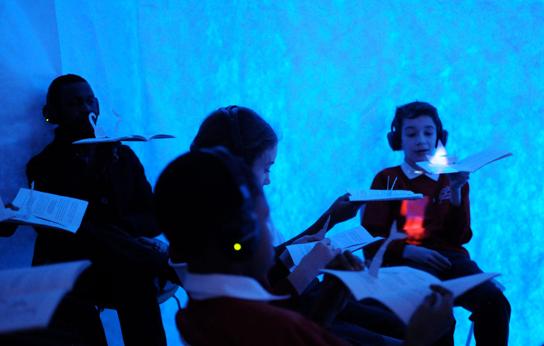 Photo of a group of children wearing headset, interacting with a book