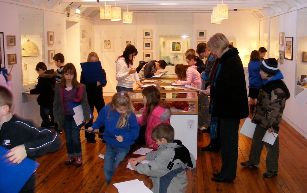 A photo of children in a gallery with pictures on the wall