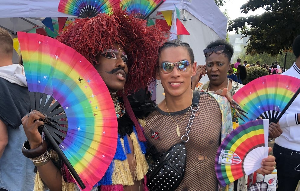 A photo of people at Pride event holding rainbow-coloured fans