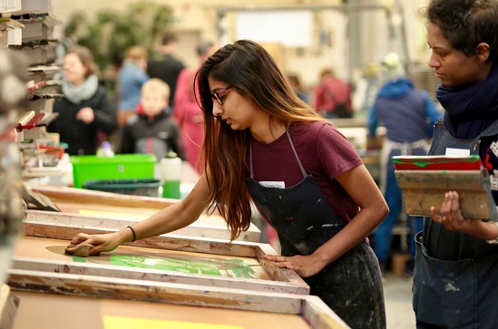 A young woman screen printing at a workshop