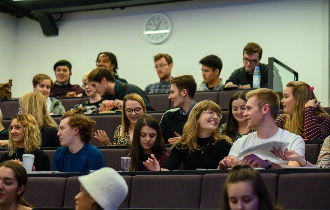 Students sitting in a lecture theatre chatting