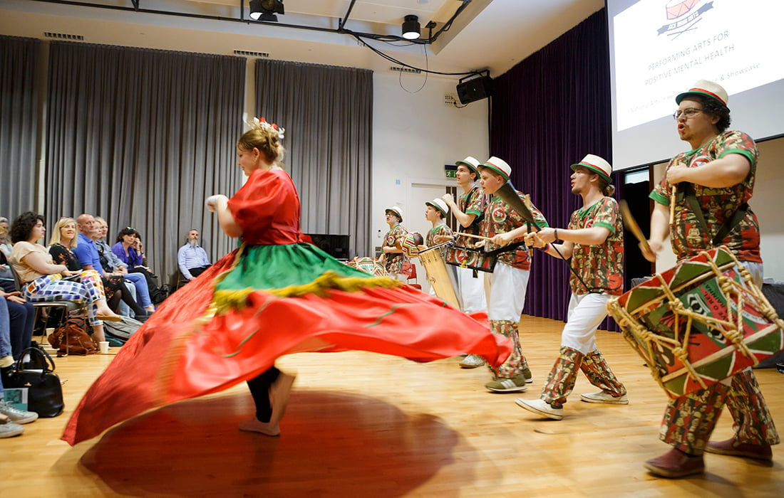 Drummers on stage following behind a woman in a huge twirling skirt