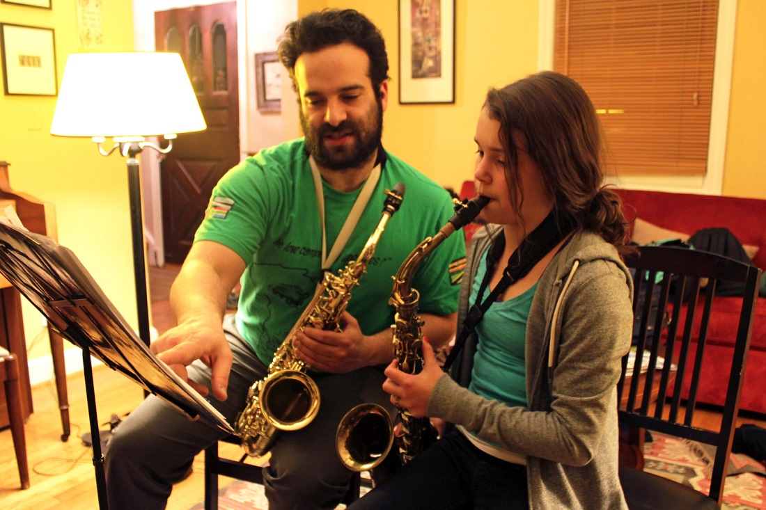 Man teaching a young girl to play saxophone