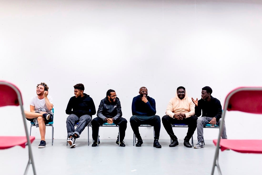 Young men sitting in a row on chairs laughing