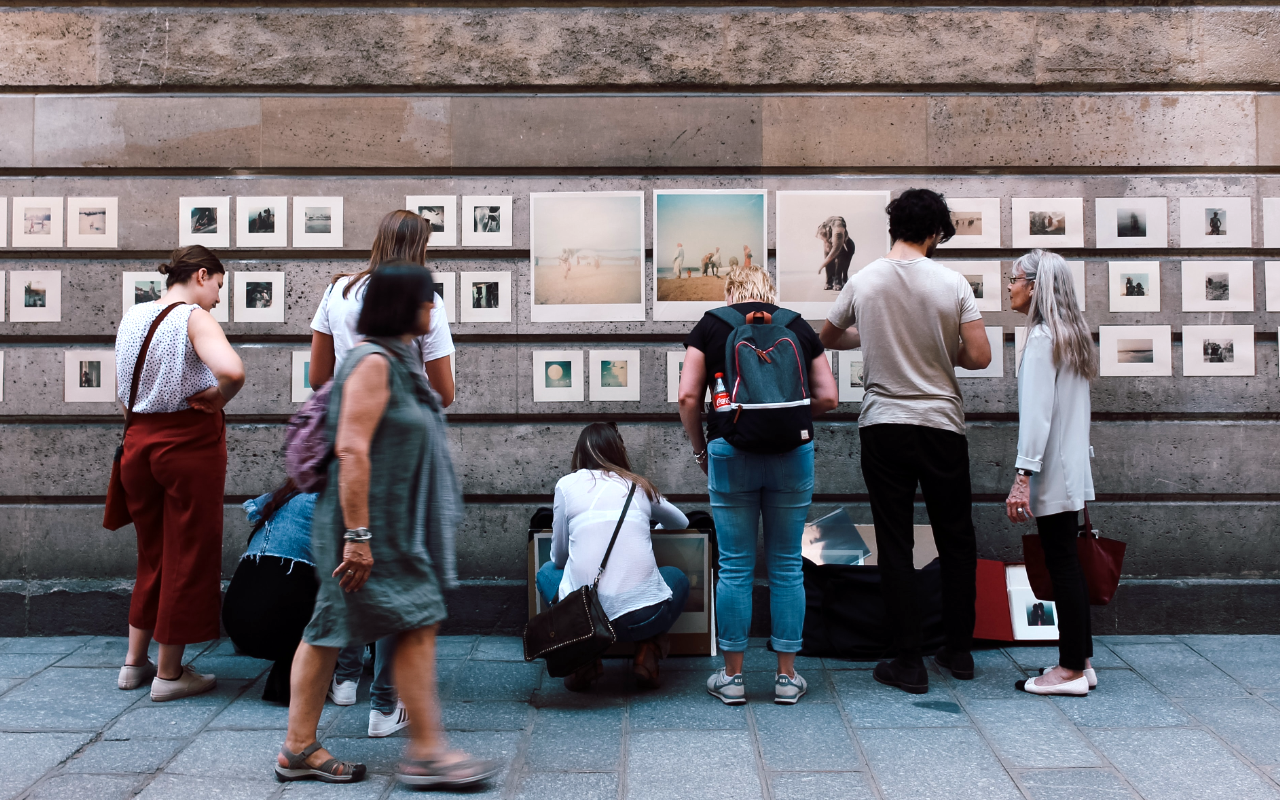 group of people looking at art on a wall outside