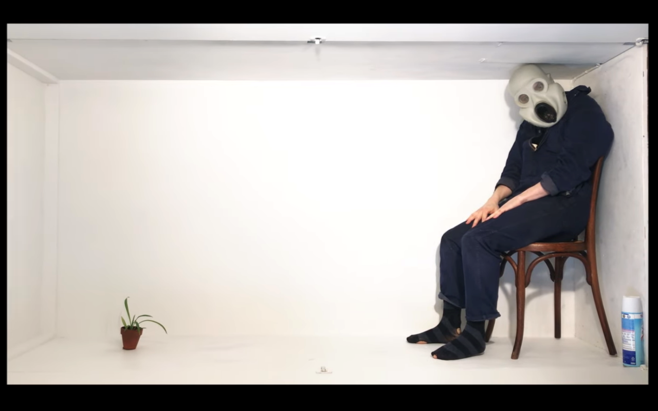 Man in a mask sitting in a low, celingless room