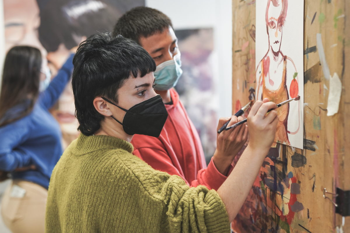 Artists in covid masks painting