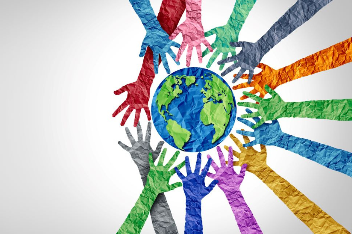 Colourful hands encircling a paper globe on a white backdrop, symbolising diverse cultures and international cooperation.