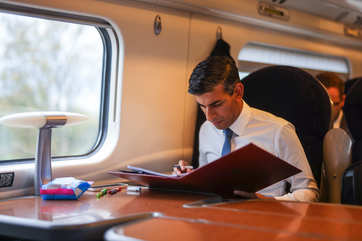 Prime Minister Rishi Sunak sat on a train reading documents