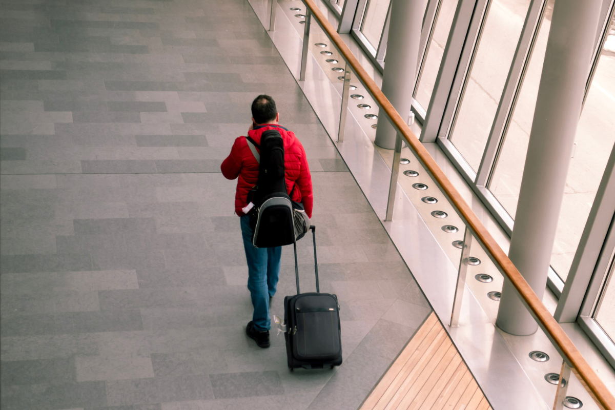 Single man traveller with a roller bag and instrument case in modern airport stock phot