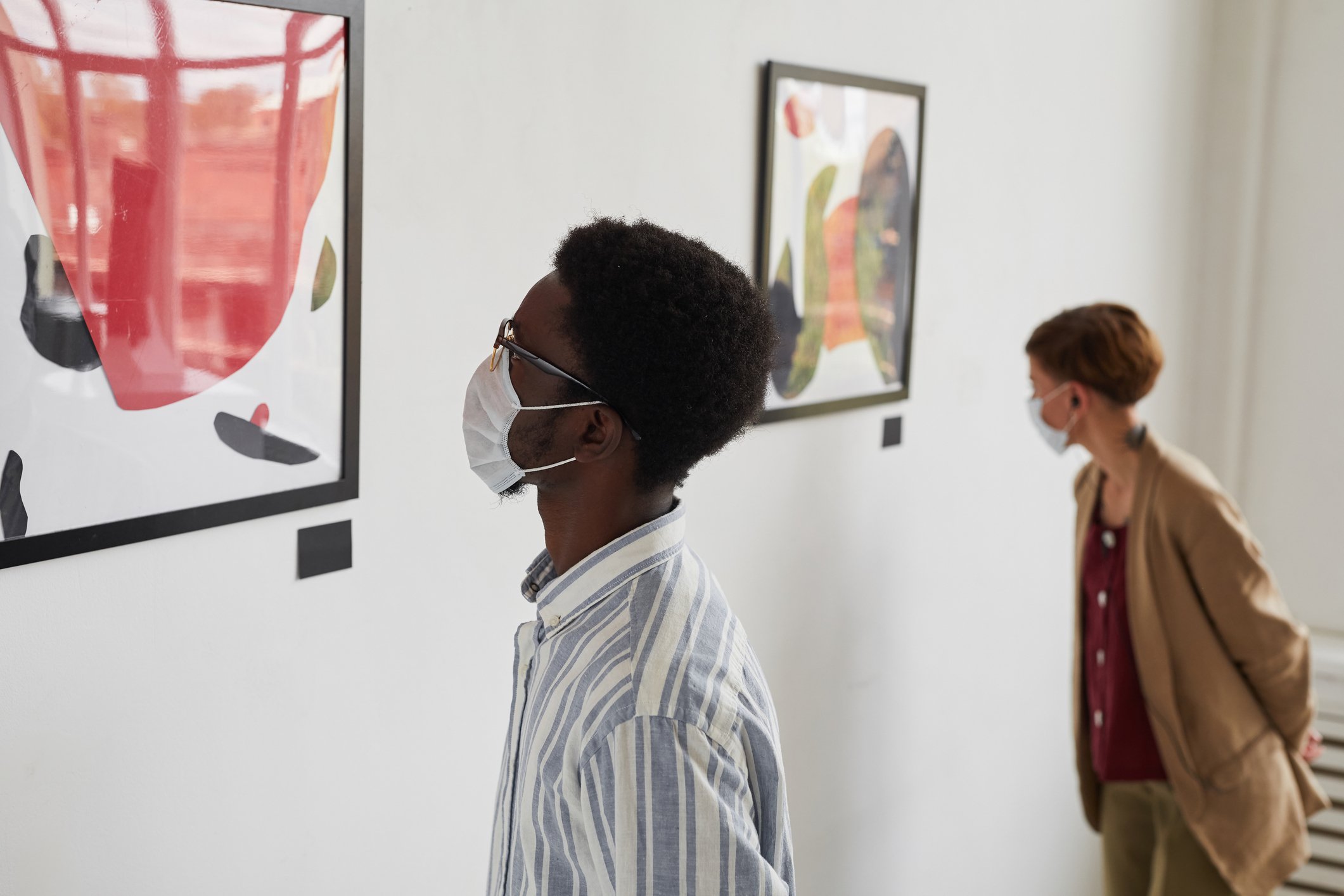 People wearing face masks looking at art