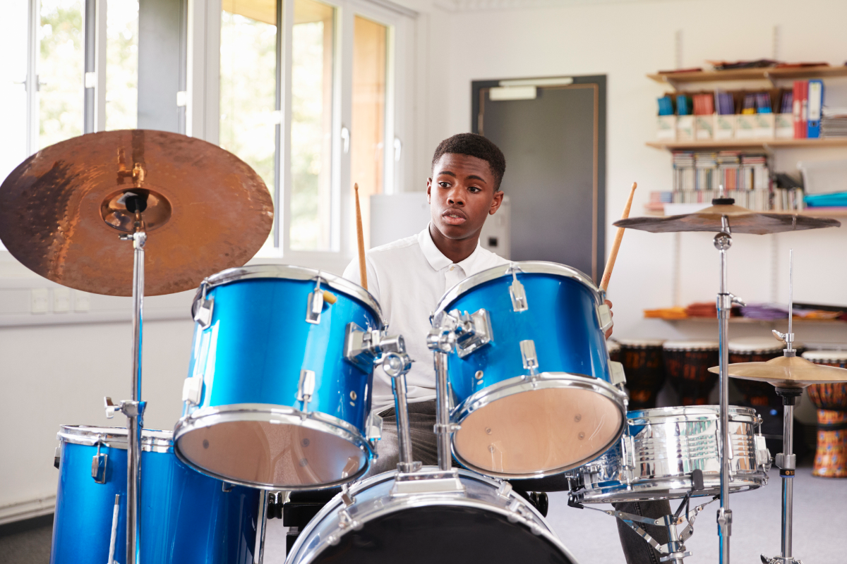 A boy sitting and playing the drums