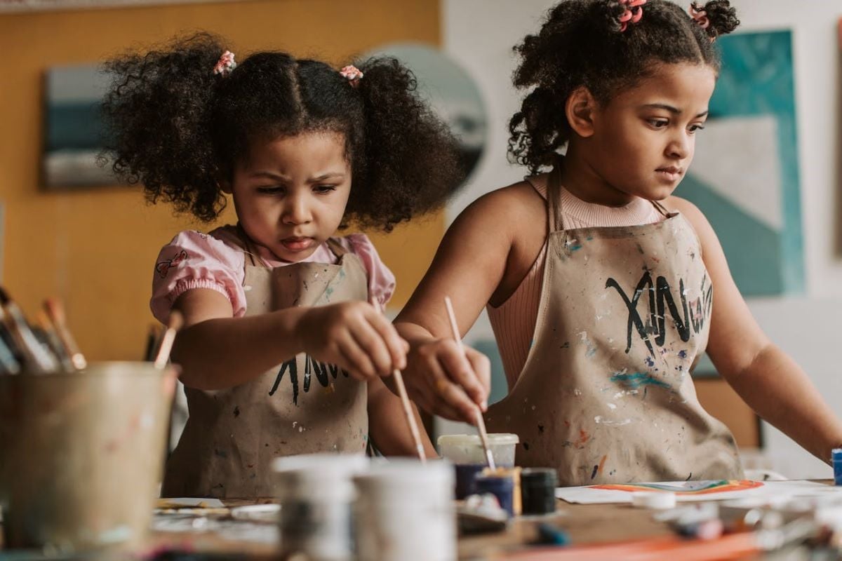 Two children standing at a table painting